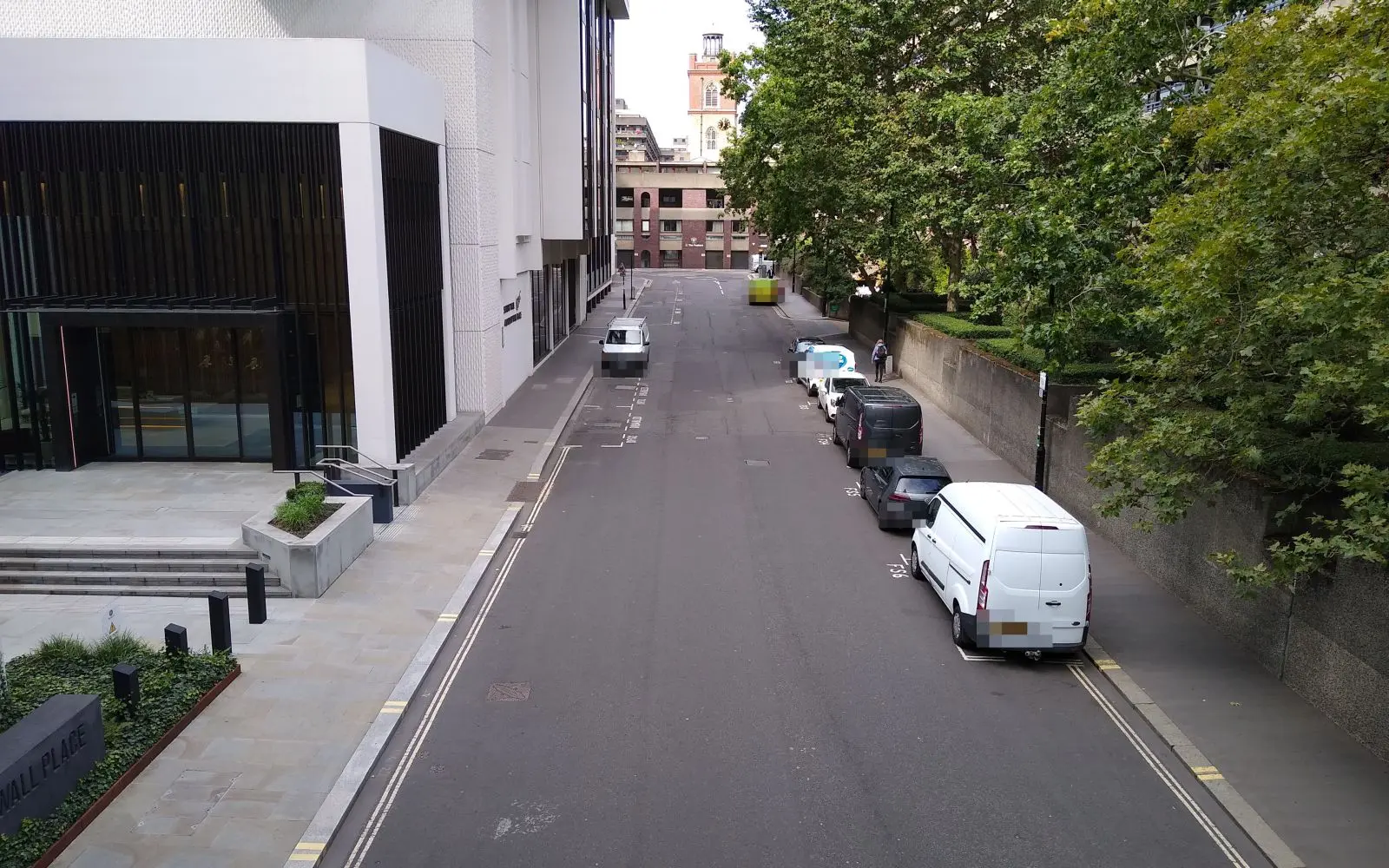 A City of London street lined with offices, trees and parked vans