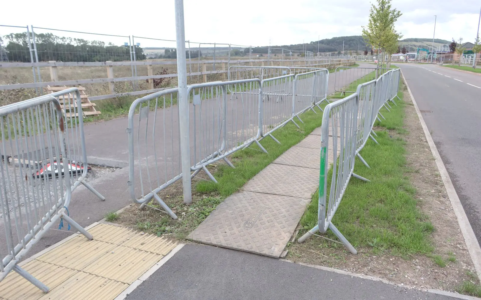 Lines of steel pedestrian barriers separating a temporary footpath from the road