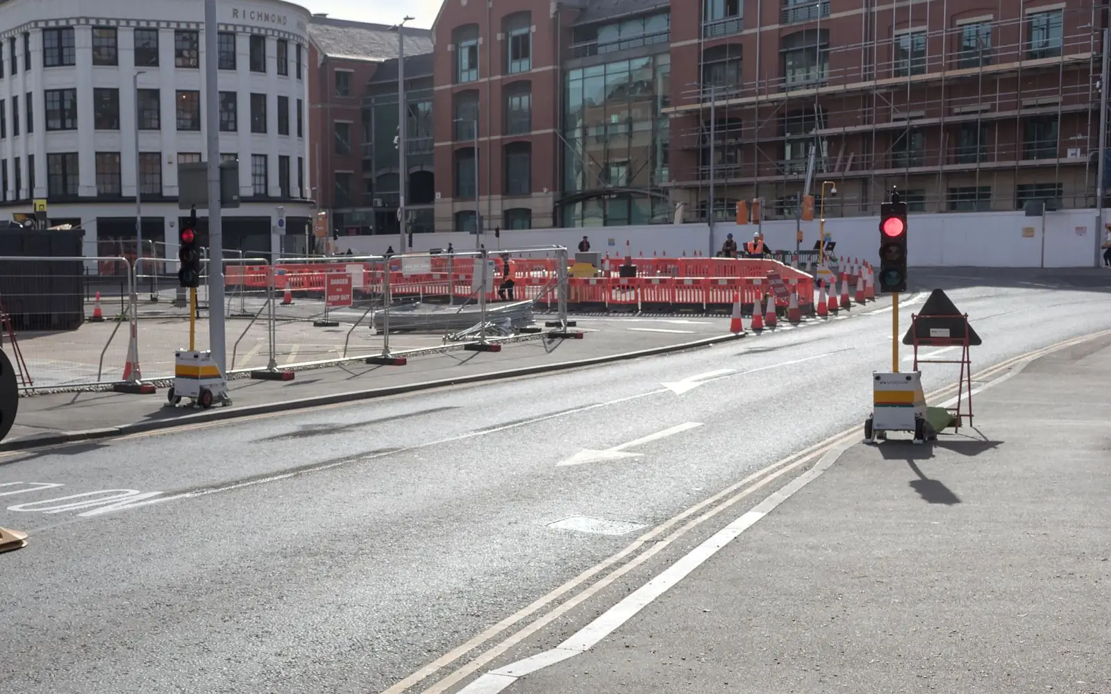 Portable traffic signals and red pedestrian barriers protecting roadworks at a city junction